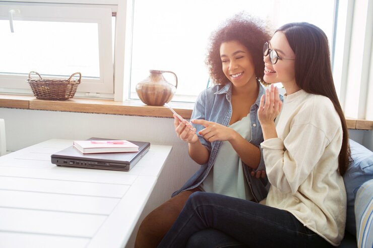 two-lovely-girls-are-sitting-together-table-they-are-looking-phone-smiling-students-have-lots-fun-together_152404-1266